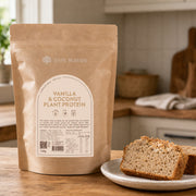 Vanilla and Coconut Plant Protein 750g pouch beside sliced coconut bread in a kitchen